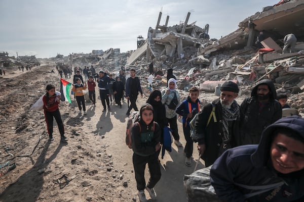 Palestinians walk through the destruction caused by the Israeli air and ground offensive in Jabaliya, as a ceasefire deal between Israel and Hamas went into effect, Sunday, Jan. 19, 2025. (AP Photo/Abed Hajjar)