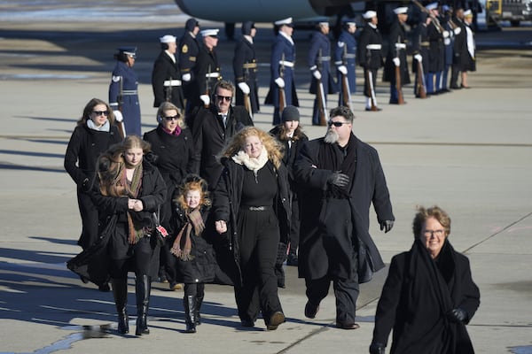 The Carter family walks off a military plane carrying the casket of former President Jimmy Carter, as they arrive at Joint Base Andrews, Md., Tuesday, Jan. 7, 2025. (AP Photo/Steve Helber)