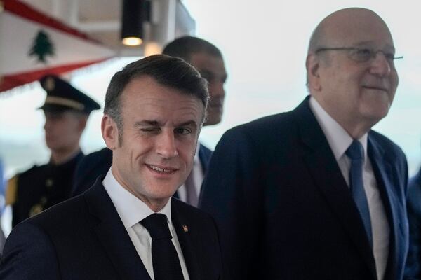 French President Emmanuel Macron winks as he walks next to Lebanese caretaker Prime Minister Najib Mikati, right, upon his arrival at Beirut's Rafic Hariri International Airport in Beirut, Lebanon, Friday, Jan. 17, 2025. (AP Photo/Hassan Ammar)