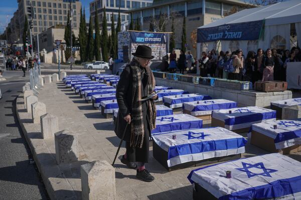 A woman walks by mock coffins lining a street and covered with Israeli flags that are meant to symbolize the price Israel will pay for agreeing to a ceasefire with Hamas in a demonstration against the deal staged by a group representing families of Israelis killed during the war in Gaza, in Jerusalem on Thursday, Jan. 16, 2025. (AP Photo/Ohad Zwigenberg)