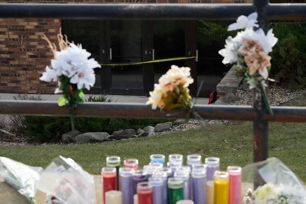 Flowers and candles are placed outside the Abundant Life Christian School Tuesday, Dec. 17, 2024 in Madison, Wis., following a shooting on Monday. (AP Photo/Nam Y. Huh)