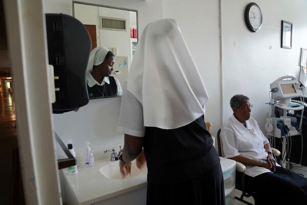 Sister Seyram Mary Adzokpa of the Sisters of the Holy Family cares for Sr. Clara Mae Jackson at the motherhouse in New Orleans, Tuesday, June 25, 2024. (AP Photo/Jessie Wardarski)