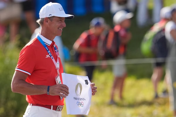 FILE - Ted Scott caddie for gold medalist Scottie Scheffler, of the United States, poses with the 18th hole flag after the end of the men's golf at the 2024 Summer Olympics, Sunday, Aug. 4, 2024, at Le Golf National in Saint-Quentin-en-Yvelines, France. (AP Photo/George Walker IV, File)