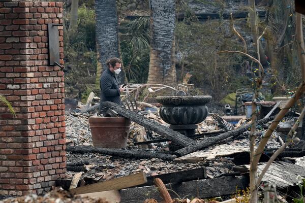 A resident sifts through their fire-damage property after the Franklin Fire swept through, Wednesday, Dec. 11, 2024, in Malibu, Calif. (AP Photo/Damian Dovarganes)