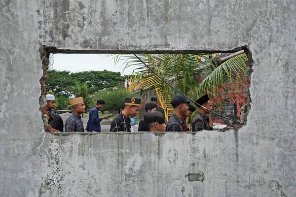 People are seen through a hole in the wall of a building damaged by 2004 Indian Ocean tsunami as they visit a giant barge housing a , a diesel power generator swept ashore by the killer wave, in Banda Aceh, Indonesia, Saturday, Dec 14, 2024. (AP Photo/Achmad Ibrahim)