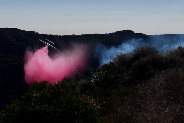 Retardant is dropped by plane on the Palisades Fire in the outskirts of the Pacific Palisades neighborhood of Los Angeles, Friday, Jan. 10, 2025. (AP Photo/Eric Thayer)