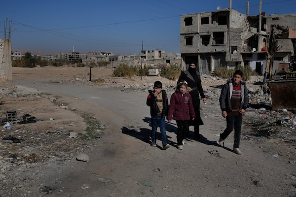 A Syrian family pass at an alley that was hit by the sarin struck during a 2013 chemical weapons attack that was blamed on then President Bashar Assad's forces, in Zamalka neighbourhood, on the outskirts of Damascus, Syria, Wednesday, Dec. 25, 2024. (AP Photo/Hussein Malla)