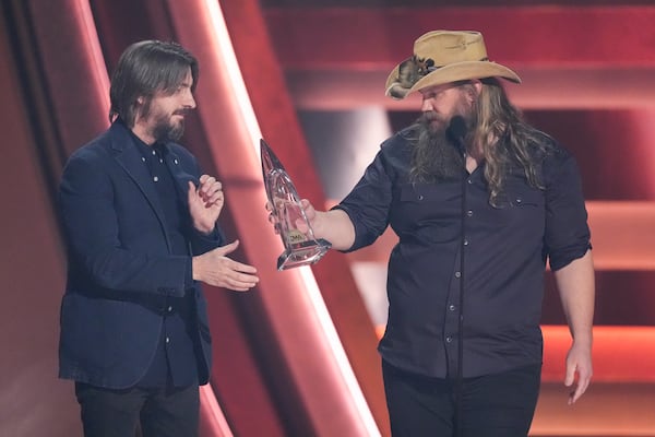 Chris Stapleton, right, passes Dave Cobb the award for single of the year for "White Horse" during the 58th Annual CMA Awards on Wednesday, Nov. 20, 2024, at Bridgestone Arena in Nashville, Tenn. (AP Photo/George Walker IV)