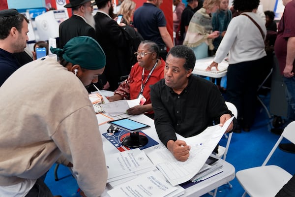 FILE - Poll workers help guide voters at a busy polling site in the Brooklyn borough of New York, Nov. 5, 2024. (AP Photo/Seth Wenig, File)