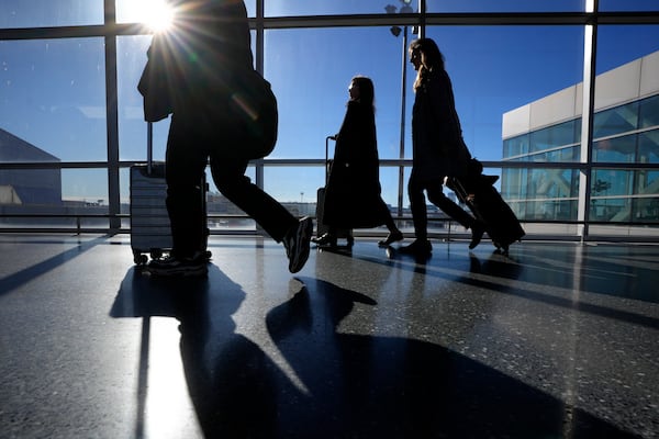 Travelers pull suitcases as they walk toward a terminal, Monday, Nov. 25, 2024, at Boston Logan International Airport, in Boston. (AP Photo/Steven Senne)