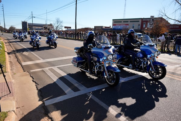 A police escort passes as the hearse carrying the flag-draped casket of former President Jimmy Carter approaches during a procession in downtown Plains, Ga., Saturday, Jan. 4, 2025. (AP Photo/Mike Stewart)