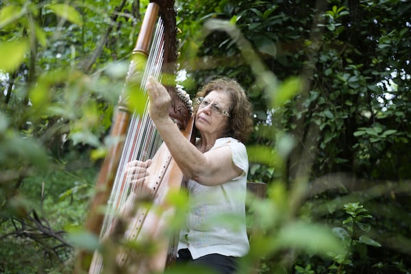 Celsa Ramirez, a former political prisoner of the Stroessner dictatorship, plays the harp in her backyard in Ita, Paraguay, Friday, Nov. 22, 2024. Ramirez, a former militant of the Communist Party, was imprisoned between 1975 and 1978 and is still searching for her missing husband. (AP Photo/Jorge Saenz)