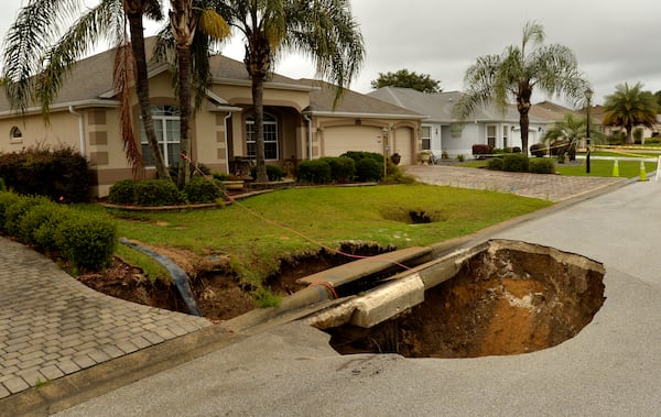 FILE - A sinkhole is shown after opening in the road at the intersection of McAlpin Street and McLawren Terrace in The Villages, Florida, on Monday, May 21, 2018. (George Horsford/Daily Sun via AP, File)