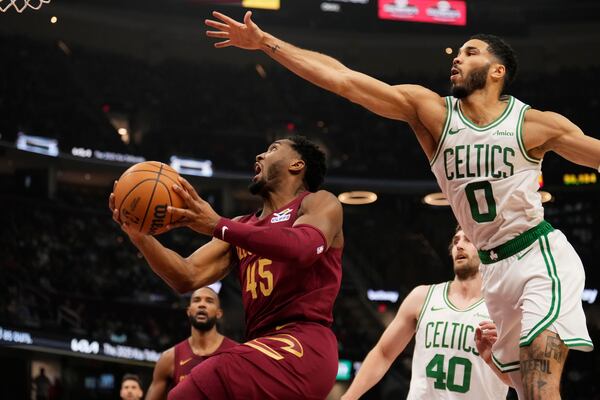 Cleveland Cavaliers guard Donovan Mitchell (45) goes to the basket in front of Boston Celtics forward Jayson Tatum (0) in the first half of an NBA basketball game, Sunday, Dec. 1, 2024, in Cleveland. (AP Photo/Sue Ogrocki)