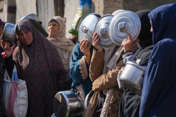 Women cover their faces as they line up to receive donated food at a distribution center for displaced Palestinians in Deir al-Balah, Gaza Strip, on Dec. 17, 2024. (AP Photo/Abdel Kareem Hana)