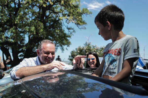 Alvaro Delgado, candidate for the ruling National Party, talks to a boy after voting in the presidential run-off election in Montevideo, Uruguay, Sunday, Nov. 24, 2024. (AP Photo/Jon Orbach)