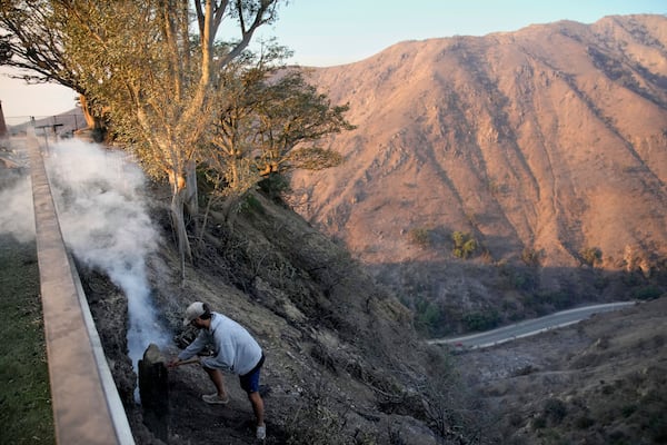 Garrett Yost gathers puts out hotspots from his neighbors' fire-ravaged properties in the aftermath of the Palisades Fire in the Pacific Palisades neighborhood of Los Angeles, Friday, Jan. 10, 2025. (AP Photo/John Locher)