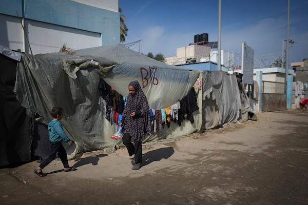 A woman and a child walk outside their tent at a camp for displaced Palestinians in Deir al-Balah, central Gaza Strip, Friday Jan. 17, 2025. (AP Photo/Abdel Kareem Hana)