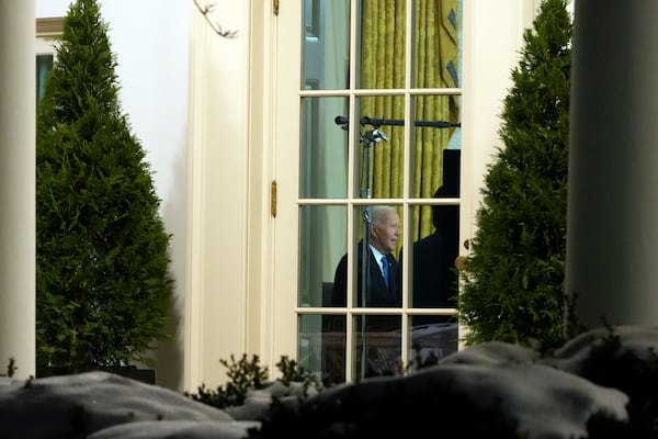 As seen through a window from the Colonnade outside the Oval Office, President Joe Biden speaks during his farewell address at the White House in Washington, Wednesday, Jan. 15, 2025. (AP Photo/Mark Schiefelbein)