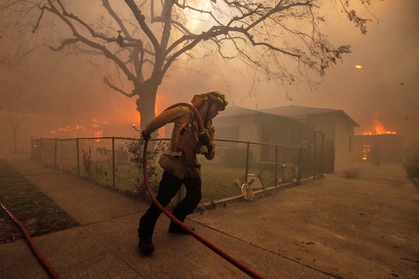 A firefighter protects a structure as the Eaton Fire advances Wednesday, Jan. 8, 2025 in Altadena, Calif. (AP Photo/Ethan Swope)