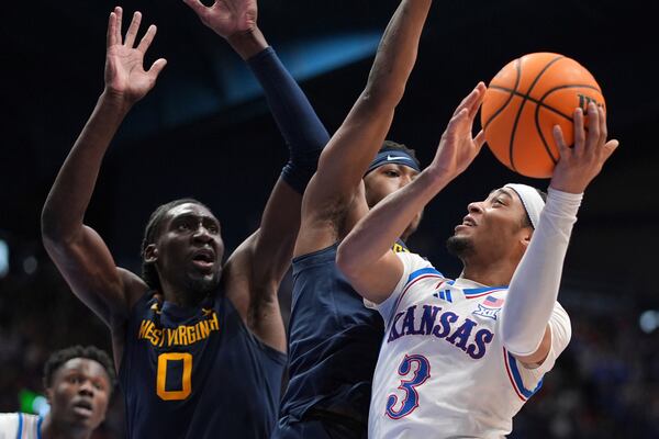 Kansas guard Dajuan Harris Jr. (3) looks to shoot under pressure from West Virginia guard KJ Tenner, center, and center Eduardo Andre (0) during the first half of an NCAA college basketball game, Tuesday, Dec. 31, 2024, in Lawrence, Kan. (AP Photo/Charlie Riedel)