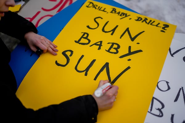 Climate activist Luisa Neubauer paints a poster as she takes part in a small protest at the Annual Meeting of World Economic Forum in Davos, Switzerland, Wednesday, Jan.22, 2025. (AP Photo/Markus Schreiber)