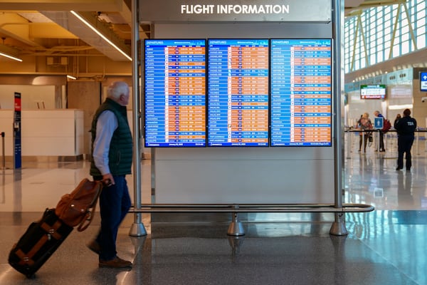 A passenger walks past a flight information board displaying several canceled flights at Ronald Reagan Washington National Airport, Thursday, Jan. 30, 2025, in Arlington, Va. (AP Photo/Stephanie Scarbrough)