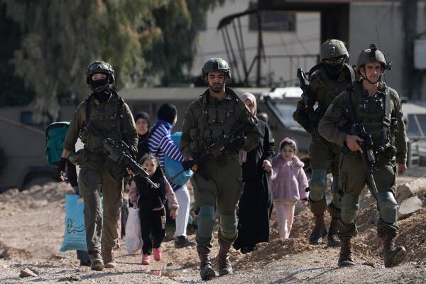 Israeli soldiers walk ahead of Palestinians displaced by an Israeli military operation from the Jenin refugee camp in the West Bank carrying their belongings on Thursday, Jan. 23, 2025. (AP Photo/Majdi Mohammed)