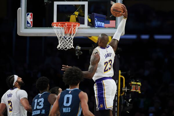 Los Angeles Lakers forward LeBron James (23) dunks the ball as forward Anthony Davis (3), Memphis Grizzlies forward Jaren Jackson Jr. (13) and forward Jaylen Wells (0) watch during the first half of an NBA basketball game, Sunday, Dec. 15, 2024, in Los Angeles. (AP Photo/Jessie Alcheh)