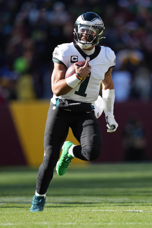 Philadelphia Eagles quarterback Jalen Hurts (1) running with the ball during the first half of an NFL football game against the Washington Commanders, Sunday, Dec. 22, 2024, in Landover, Md. (AP Photo/Stephanie Scarbrough)