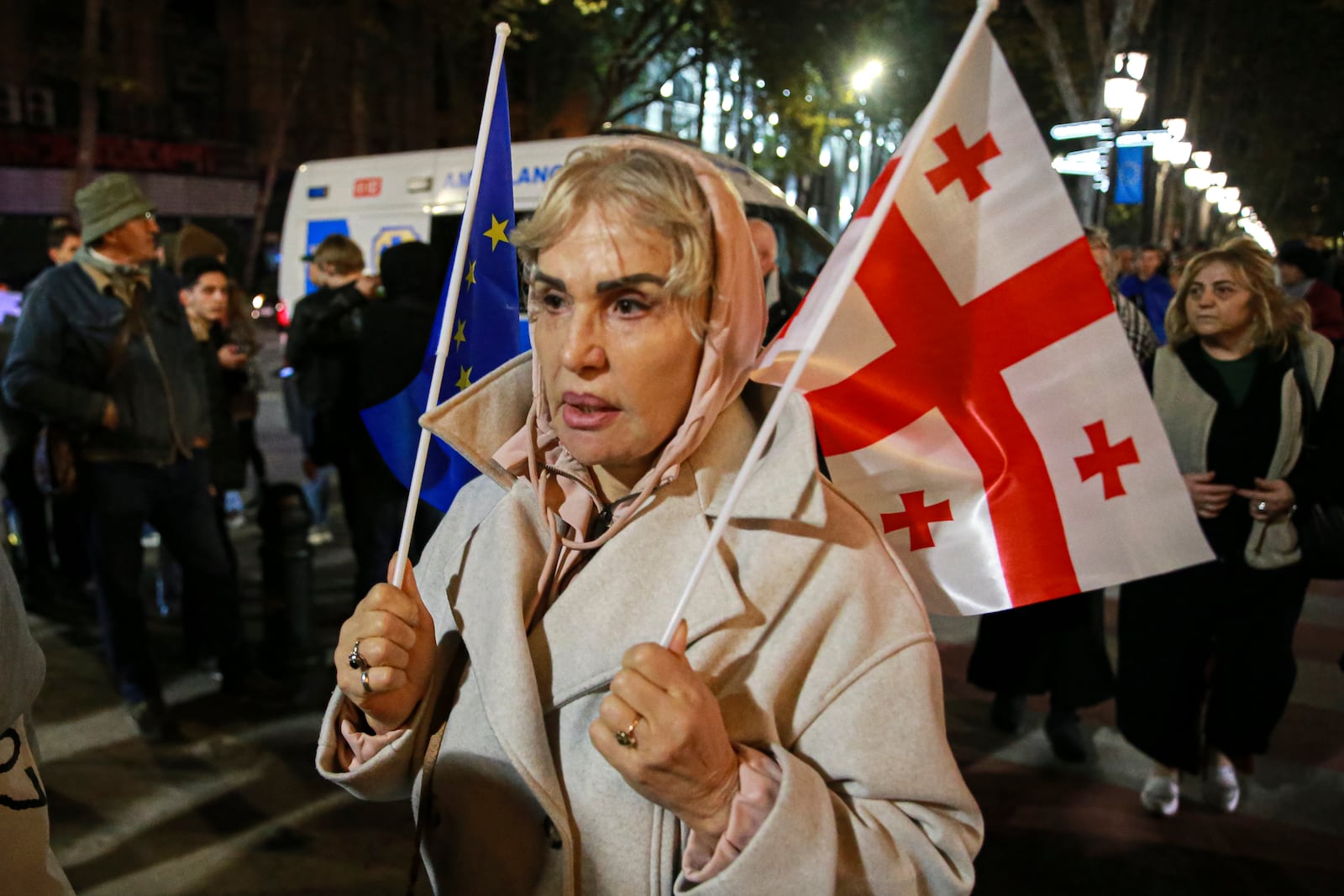 A demonstrator holds an EU and a Ukrainian national flags during an opposition protest agains the results of the parliamentary election in Tbilisi, Georgia, Monday, Oct. 28, 2024. (AP Photo/Zurab Tsertsvadze)