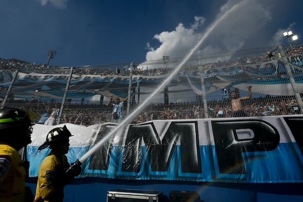 Firefighters shoot water into the crowd during the Copa Sudamericana final soccer match between Argentina's Racing Club and Brazil's Cruzeiro in Asuncion, Paraguay, Saturday, Nov. 23, 2024. (AP Photo/Gustavo Garello)