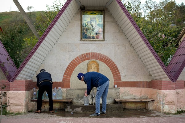 FILE - Men collect water from a fountain in the village of Hrusevo, Moldova, Sunday, Oct. 20, 2024. (AP Photo/Vadim Ghirda, File)