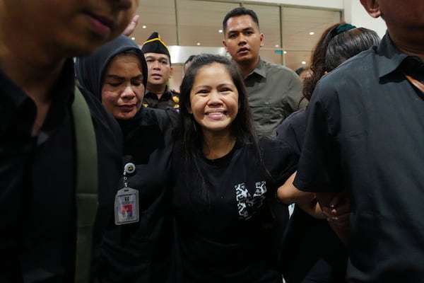 Mary Jane Veloso, center, a Filipina who was on death row in Indonesia and was nearly executed by firing squad in 2015, smiles as she arrives at Soekarno-Hatta International Airport for her repatriation to the Philippines, in Tangerang, Indonesia, Tuesday, Dec. 17, 2024. (AP Photo/Tatan Syuflana)