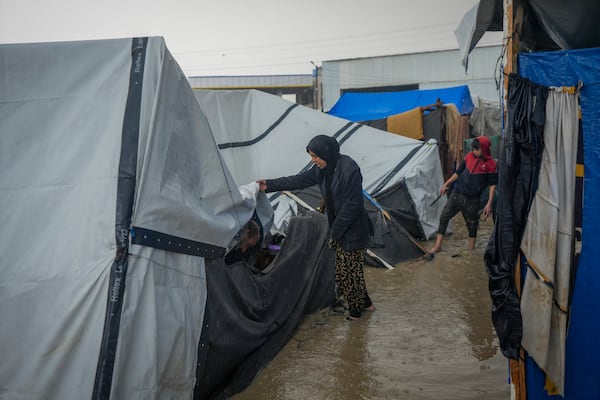 Manal Lubbad, a 49-year-old mother of eight and a displaced woman from Gaza City, tries to repair her flooded and damaged tent after heavy overnight rainfall at the refugee tent camp for displaced Palestinians in Deir al-Balah, central Gaza Strip, Tuesday, Dec. 31, 2024. (AP Photo/Abdel Kareem Hana)