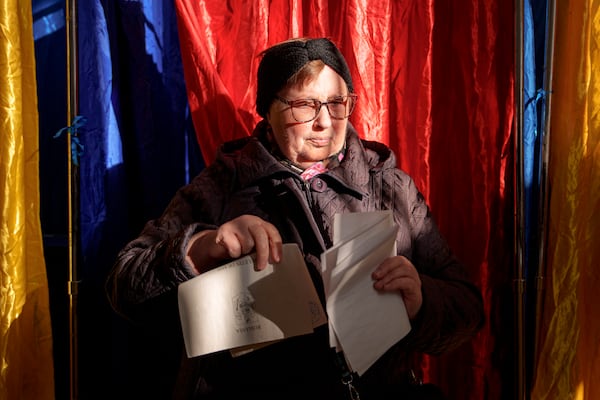 A woman exits a voting booth before casting her vote in the country's presidential elections, in Bucharest, Romania, Sunday, Nov. 24, 2024. (AP Photo/Andreea Alexandru)