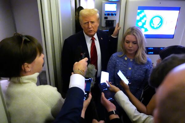 President Donald Trump speaks to reporters aboard Air Force One en route from Miami to Joint Base Andrews, Md., Monday, Jan. 27, 2025, as White House press secretary Karoline Leavitt listens. (AP Photo/Mark Schiefelbein)