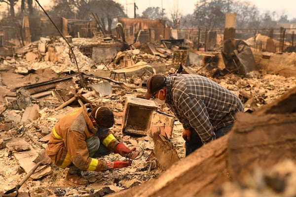 Robert Lara, left, looks for belongings along with his stepfather after the Eaton Fire burns in Altadena, Calif., Thursday, Jan. 9, 2025. (AP Photo/Nic Coury)