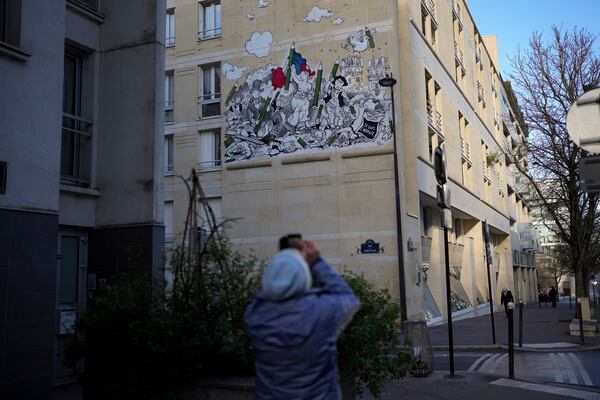 A woman takes a snapshot of a fresco by French street artist Nilko referring to the "Liberty Leading the People" painting by Eugene Delacroix during commemorations marking 10 years since an Islamist attack on the Charlie Hebdo satirical newspaper and the Hypercacher jewish supermarket, in Paris Tuesday Jan. 7, 2025. (AP Photo/Thibault Camus)