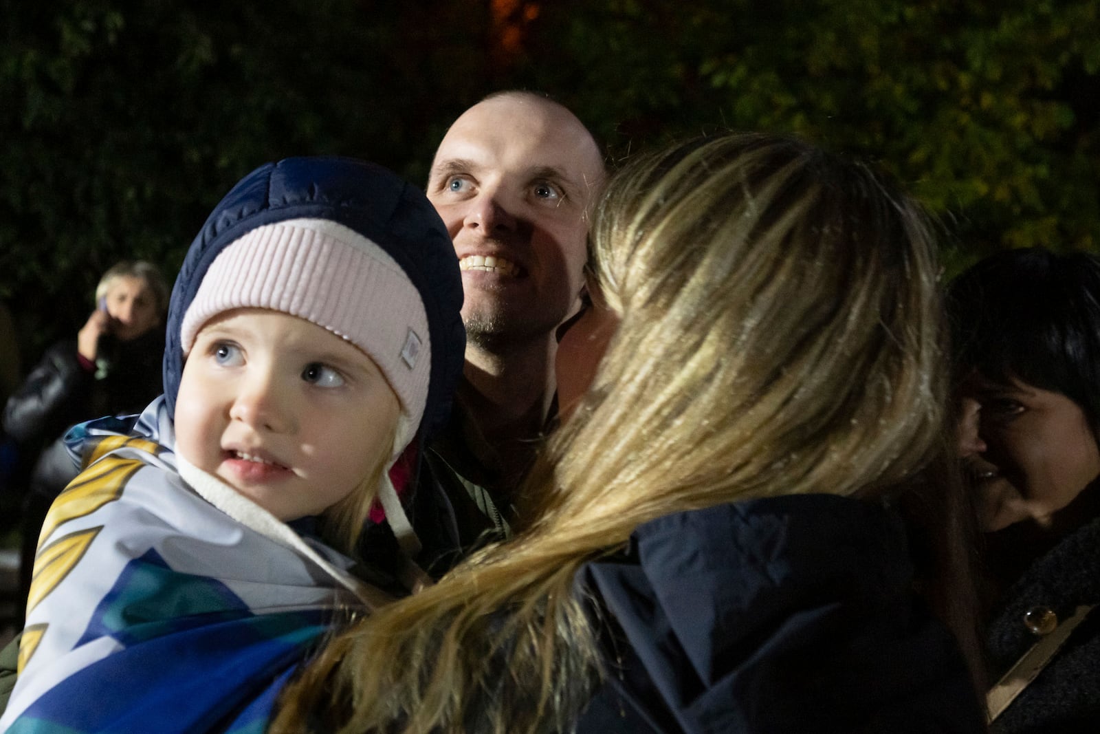 In this photo provided by the Press Service of the President of Ukraine on Oct. 19, 2024, a Ukrainian serviceman hugs his family after returning from captivity during a POWs exchange in an undisclosed location, Ukraine. (Press Service of the President of Ukraine via AP)