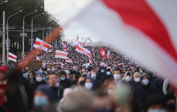 FILE - People carrying an old Belarusian national flag ,that has become an anti-government symbol, march in an opposition rally to protest the presidential election results in Minsk, Belarus, on Oct. 18, 2020. (AP Photo, File)