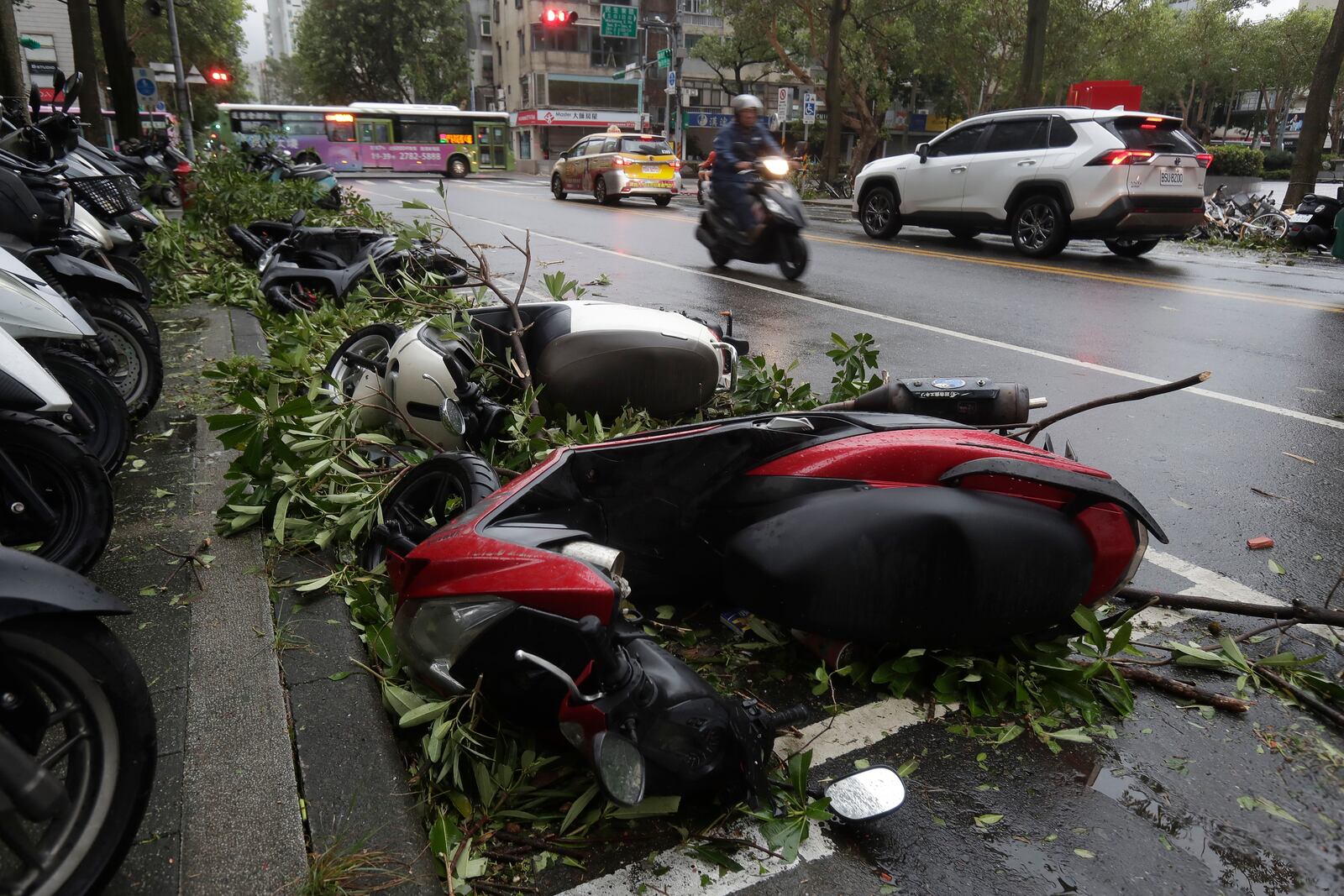 A motorcyclist drives past a row of upside down motorbikes after Typhoon Kong-rey leaves in Taipei, Taiwan, Friday, Nov. 1, 2024. (AP Photo/Chiang Ying-ying)