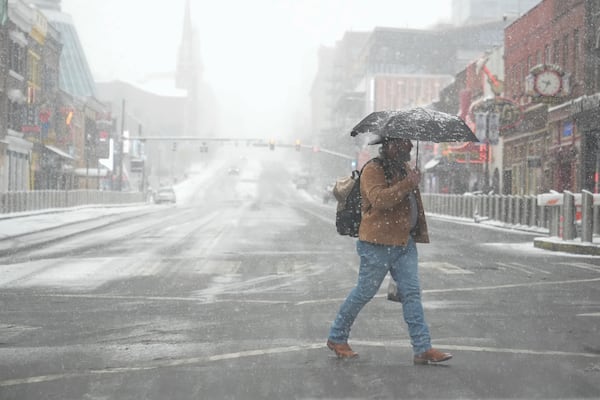 A person walks across Broadway in the snow Friday, Jan 10, 2025, in Nashville, Tenn. (AP Photo/George Walker IV)