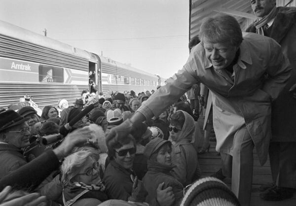 FILE - President-elect Jimmy Carter leans over to shake hands with some of the people riding the "Peanut Special" to Washington, Jan. 19, 1977. They will travel all night, arriving in Washington in time for Carter's inauguration as president on Jan. 20. (AP Photo, File)