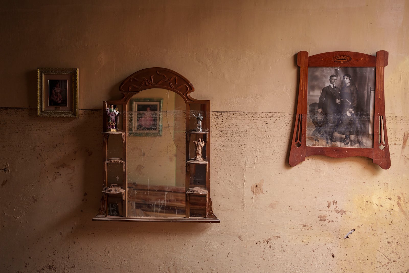 The water level is visible on a wall next to some family photographs in Valencia, Spain, Saturday, Nov. 2, 2024. (AP Photo/Manu Fernandez)