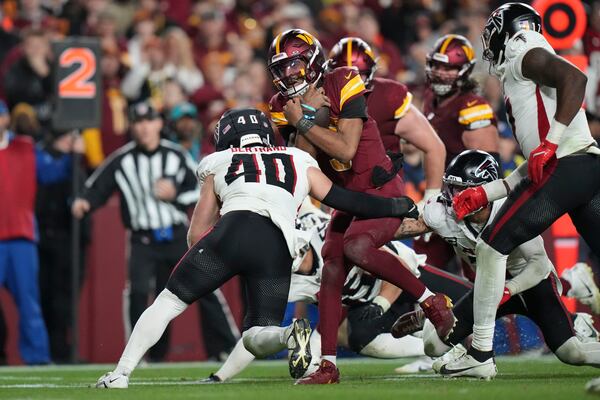 Washington Commanders quarterback Jayden Daniels carries abasing Atlanta Falcons linebacker JD Bertrand (40) in overtime during an NFL football game, Sunday, Dec. 29, 2024, in Landover, Md. The Commanders won 30-24. (AP Photo/Stephanie Scarbrough)