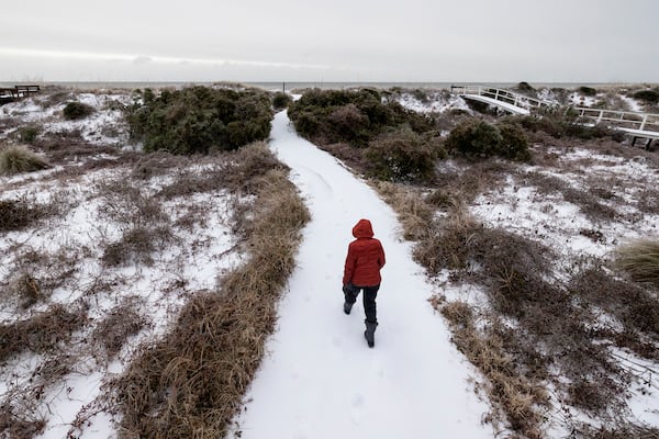 A beach walker heads to the ocean after a winter storm dropped ice and snow Wednesday, Jan. 22, 2025, on the Isle of Palms, S.C. (AP Photo/Mic Smith)