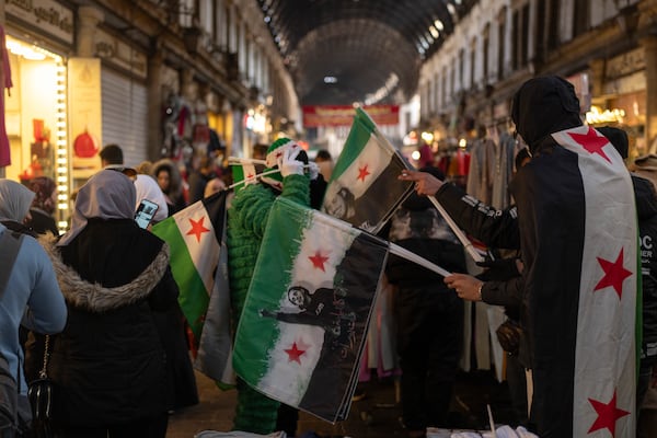 A vendor sells new Syrian flags in Al-Hamidiyeh Souq on New Years Eve, in Damascus, Syria, Tuesday, Dec. 31, 2024. (AP Photo/Mosa'ab Elshamy)