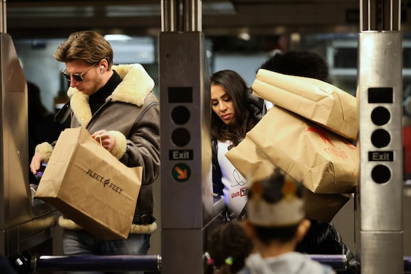 Shoppers manage their bags as they enter a Subway turnstile, Friday, Nov. 29, 2024, in New York. (AP Photo/Heather Khalifa)