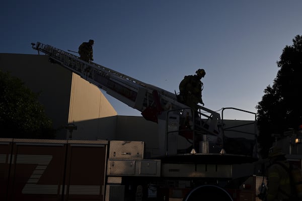 Firefighter walk down a ladder outside a building where a plane crash occurred Thursday, Jan. 2, 2025, in Fullerton, Calif. (AP Photo/Kyusung Gong)